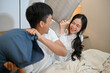 © bongkarn - A lovely and playful young Asian couple are playing a pillow fight in the bedroom.