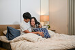 © bongkarn - A lovely young Asian couple in pajamas are hugging, playing, and cuddling in bed.