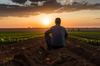 Farmer taking moment of quiet reflection at the end of long day and watching the sun dip below the sunset. Generative AI