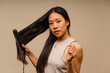 © Nuria Seguí/Stocksy - Asian Woman Using Hair Straightener
