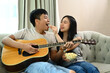 © Prathankarnpap - Happy man playing guitar while his wife feeding him with popcorns, enjoy weekend activity together