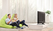 © Ljupco Smokovski - Man and woman eating popcorn nd sitting on beanbags in front of tv