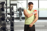 Fototapeta Panele - Man at a gym, holding his red painful shoulder