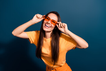 Poster - Portrait of good mood adorable woman wear stylish t-shirt hands hold sunglass toothy smiling isolated on dark blue color background