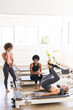© Wavebreak Media - Biracial women exercising on Pilates reformers in a bright fitness studio with copy space