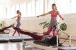 © Wavebreak Media - Young Caucasian woman instructs a biracial woman on Pilates reformer
