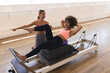 © Wavebreak Media - Young Caucasian woman instructs biracial woman on Pilates reformer