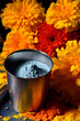 A cup of dark Holi powder against a backdrop of bright marigold flowers.