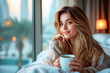 A young woman enjoys a cozy morning with coffee in bed, overlooking a cityscape from a high-rise hotel.