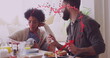 Image of hearts over happy diverse couple eating and talking