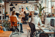 Robot works at computer in an office among people. IT team of the future. The concept of artificial intelligence and people working in the future