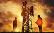 © ฺฺฺBoonterm - Silhouette Engineer worker man and woman working wearing helmets doing field work telecommunication tower holding blueprints controlling installation connectivity equipment maintaining 5G network.