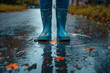 Close up wearing rubber boots and splashing water on puddle