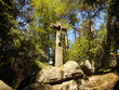 A stone cross on the rocks, in the middle of the forest.