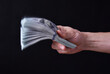Man holding around 10000 US dollars, 100 USD banknotes. Blurred batch of money.