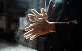 Fototapeta  - Chef clapping flour off hands in dramatic kitchen light