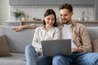 © Prostock-studio - Happy young european couple browsing on laptop at home