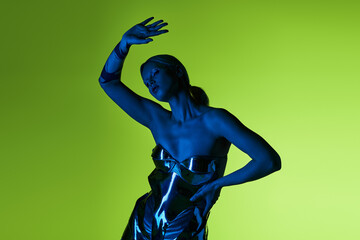 peculiar alluring woman in futuristic sci fi attire posing in blue lights on green backdrop