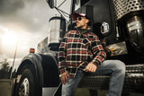 Fototapeta Zachód słońca - American Semi Truck Driver in Front of His Heavy Duty Vehicle