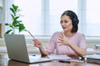 © Valerii Honcharuk - Young female college student in headphones studying using laptop computer for video chat