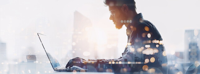 Wall Mural - The double exposure image of the business man using a laptop computer overlay with cityscape image. The concept of business, freelance, online working, surfing the internet