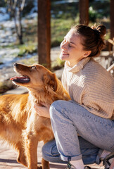 Young adult happy woman playing with her retriever dog on the terrace of a country house in early spring