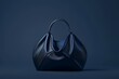 A sophisticated black handbag rests upon a vibrant blue background, creating a striking contrast that exudes elegance and style.
