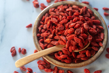 Wall Mural - Dried  goji berries in ceramic plate with wooden spoon.