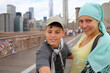 A woman in a blue headscarf with her son on the walking part of the Brooklyn Bridge