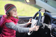© Pavel Losevsky - Happy little girl in pink waistcoat and striped hat sitting at wheel of car