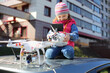 © Pavel Losevsky - Little girl in striped hat sitting on top of car with radio control in her hands and quadcopter