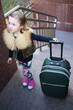 © Pavel Losevsky - Pretty little girl standing with a large green suitcase on stairs