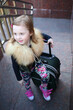 © Pavel Losevsky - Happy little girl standing with a large green suitcase on stairs