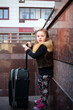 © Pavel Losevsky - Pretty little girl stands with a large green suitcase near wall