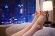 © Pavel Losevsky - Woman puts her feet with red pedicure on pillow near window with city view