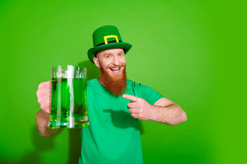 Wall Mural - Portrait of funky handsome guy indicate finger beer ginger ale mug empty space isolated on green color background