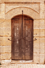 Wall Mural - Closed ancient wooden door with metal chain across outside on stone facade