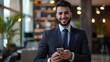 © Poorna Himasha - business person in formal suit smiling looking at mobile in his hands confident and vision in modern interir office background