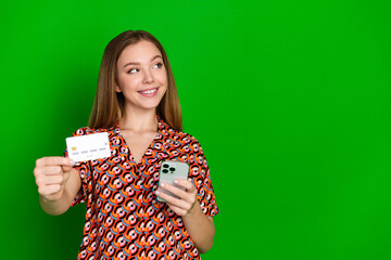 Sticker - Photo of nice charming girl dressed print shirt holding smartphone credit card look empty space isolated on green color background