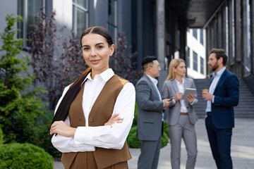 professional woman in smart casual attire confidently posing with crossed arms. colleagues conversin