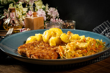 Canvas Print - Breaded pork neck cutlet served with potatoes and salad.