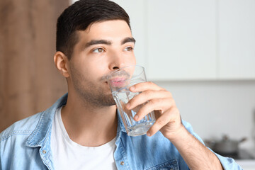 Wall Mural - Young man drinking fresh water in kitchen