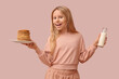Little girl with tasty pancakes and bottle of milk on beige background