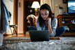 Gen Z female focused on studying, seated on the floor at home with a laptop, engaged in research and homework for college.

