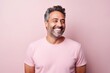 © Iigo - Portrait of handsome middle aged man laughing and looking at camera against pink background