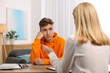 © New Africa - Psychologist working with teenage boy at table in office