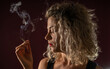 WOMAN WITH CURLERS IN A DARK ENVIRONMENT SMOKING A CIGARETTE WITH BACKLIGHT