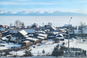 Wall Mural - Siberian village on the shore of Lake Baikal. Nizhneangarsk, Republic of Buryatia, Siberia, Russia. Winter. View of snow-covered village houses. There is a lot of snow on the ground and on the roofs.