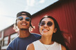portrait of a happy couple, asian young woman, black man, smiling outdoors in sunlight, near red building, wearing sunglasses, cap, casual tshirt, white tank top, relationship diversity cheerful
