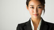 Beautiful studio portrait of young, stylish asian executive businesswoman wearing black blazer suit, looking at camera with confidence on white background.